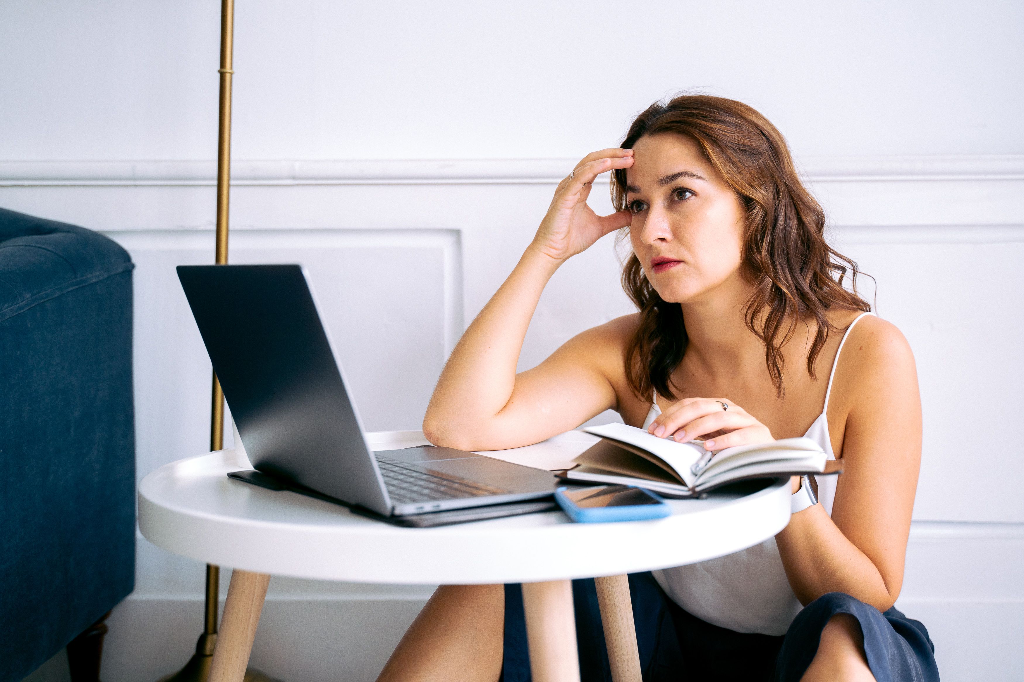 A learner sitting with a notebook and laptop while preparing for English speaking practice.